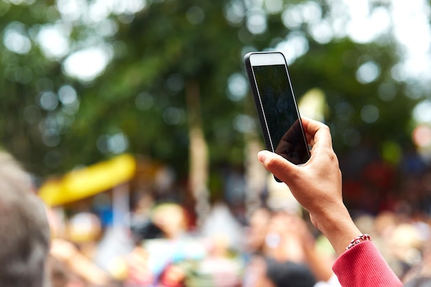 Closeup of a hand from the crowd filming the event on a cell phone