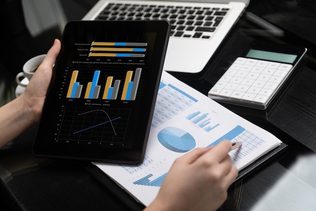 Closeup of hand holding tablet and point pen at chart