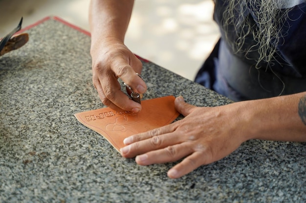 Closeup hand of leather craftsman is carefully to make a leather product for a customer