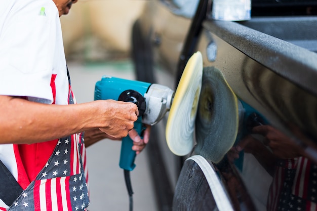 Closeup hand man polishes a black car with a polisher 