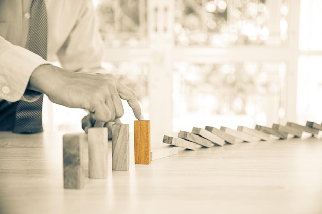 Closeup hand prevent wooden block not falling domino concepts of financial risk management and strategic planning and business challenge plan