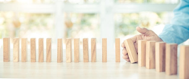 Closeup hand prevents wooden block not falling