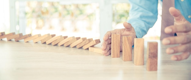 Closeup hand prevents wooden block not falling