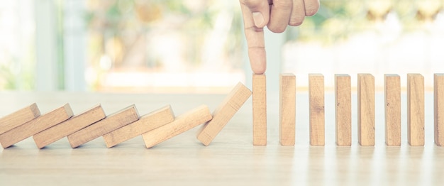 Closeup hand prevents wooden block not falling