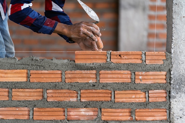 Photo closeup hand professional construction worker laying bricks in new industrial site