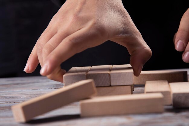 Closeup hand takes one block on a wooden block tower