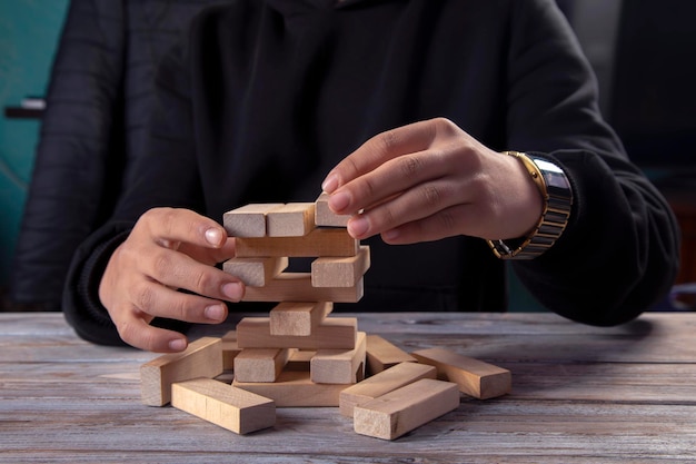 Closeup hand takes one block on a wooden block tower