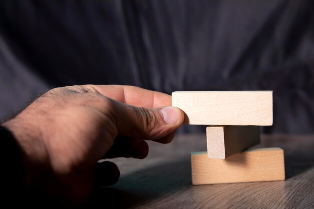 Closeup hand takes one block on a wooden block tower