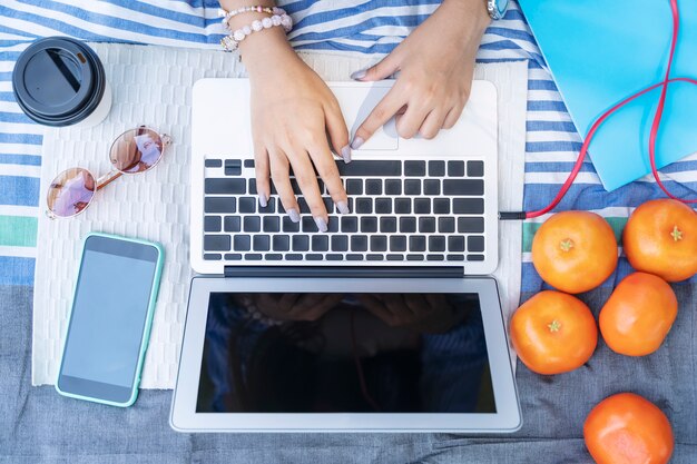 Closeup of hand using laptop with mobile and accessories on table. 