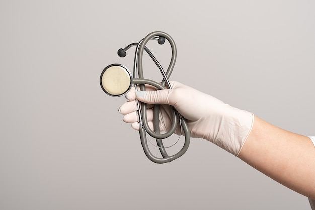 Closeup of the hand in a white sterile glove holding a stethoscope, isolated