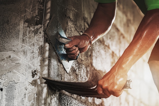 Closeup hand of worker plastering cement at wall for building house 