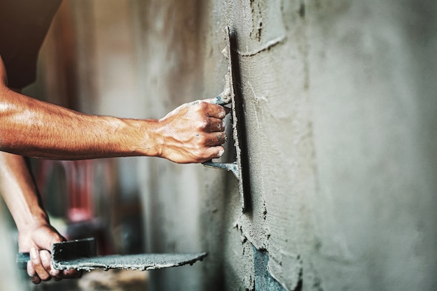 Closeup hand of worker plastering cement at wall for building house 