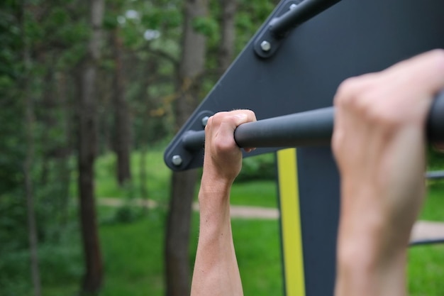 closeup of hands of athletic man on the pullup bar during pullup exercise in training