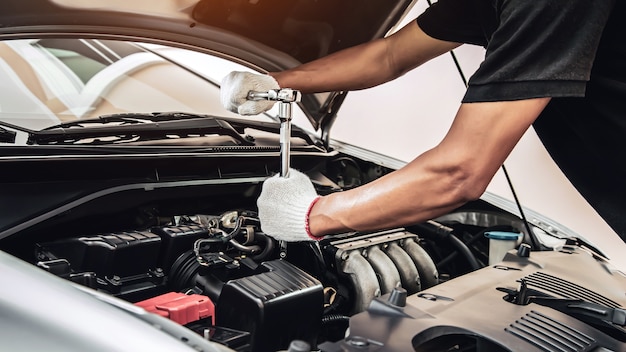 Closeup hands of auto mechanic are using the wrench to repair a car engine in auto car garage