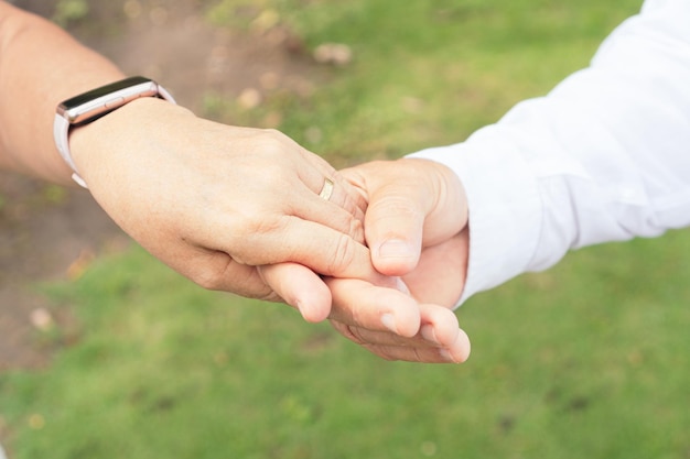 Closeup of hands of bride and groom with ring on finger Happy couple celebrating wedding outdoors