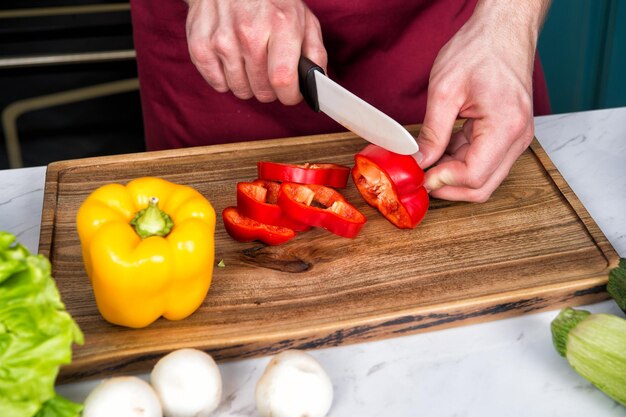 Closeup of hands cutting vegetables with knife.