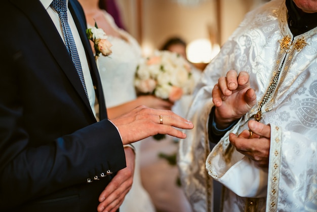 Closeup of hands of groom and priest in a church