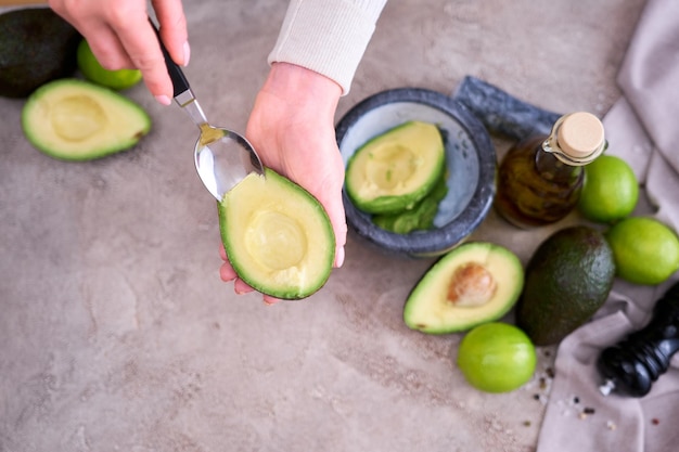 Closeup on hands holding fresh avocado cut in half making guacamole