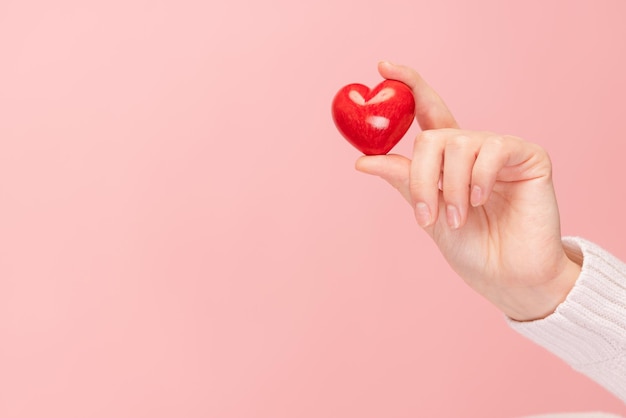 Closeup hands holding heart on pink background valentine's day concept