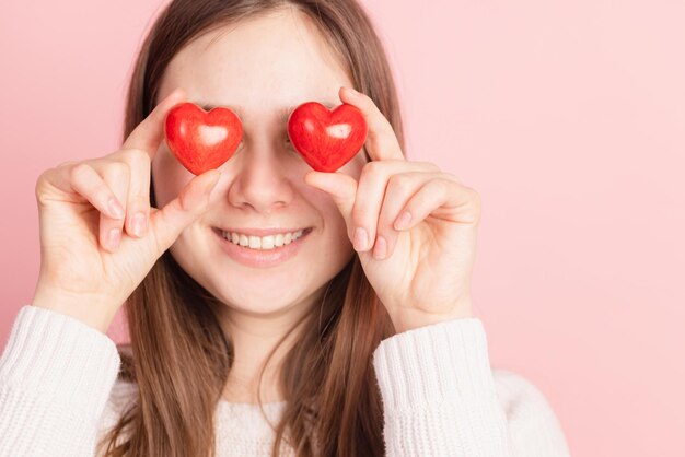 Closeup hands holding heart on pink background valentine's day concept