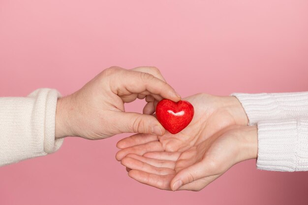 Closeup hands holding heart on pink background valentine's day concept