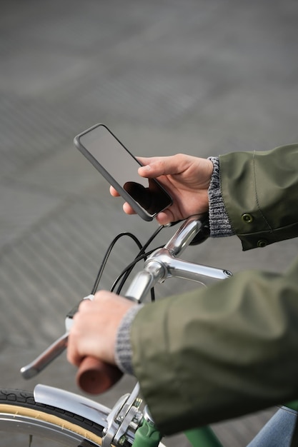 Closeup of hands holding phone and handlebars of bicycle