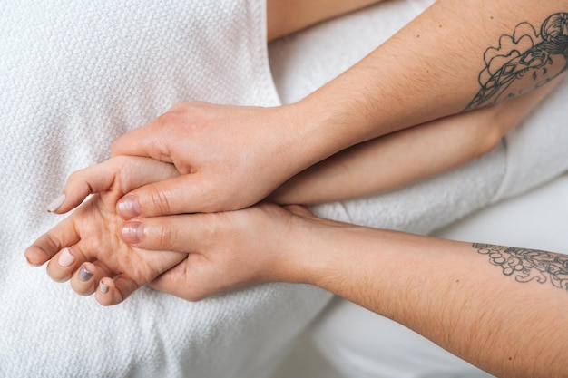 Closeup hands of male masseur doing finger and palm massage to woman lying on massage table