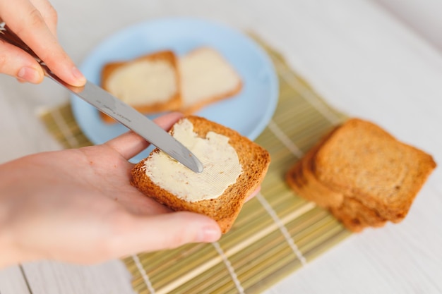 A closeup of hands spreading butter on a slice of toasted bread symbolizing a healthy and delicious