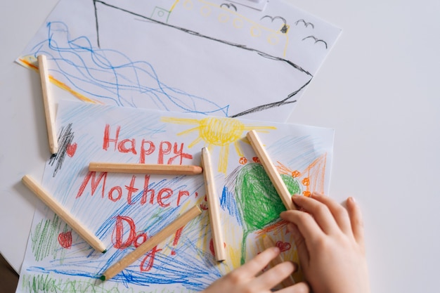 Photo closeup of hands of unrecognizable girl drawing with colored pencils at the table