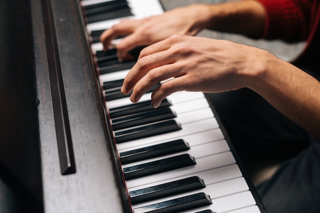 Closeup hands of unrecognizable man playing on piano at home recording studio