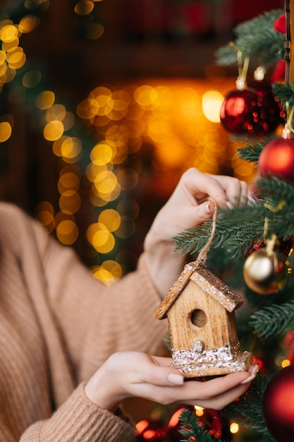 Closeup hands of unrecognizable woman holding Christmas toy on background of xmas tree