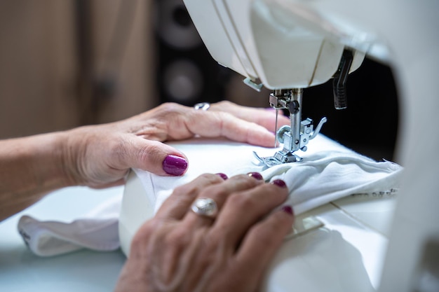 Closeup of the hands of an unrecognizable woman sewing on her sewing machine