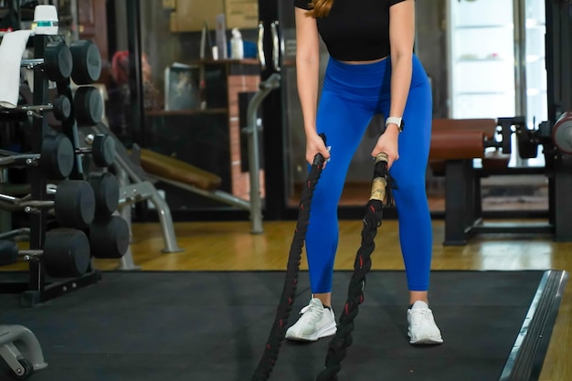 Closeup hands of young female holding black rope for ready workout training the battle rope