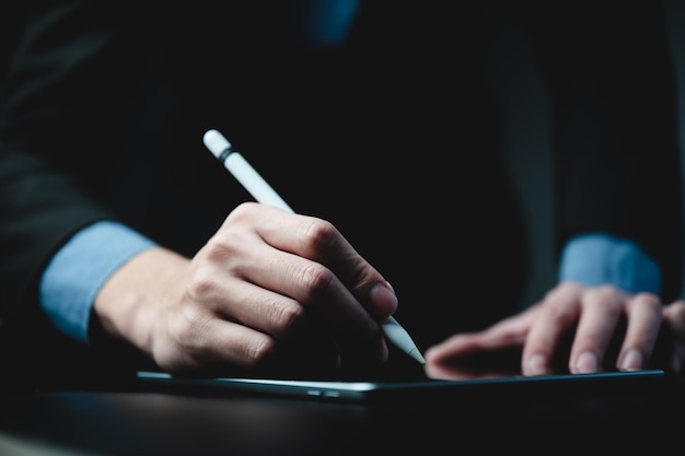 Closeup of hands of a young successful male entrepreneur and businessman writing on digital tablet using a digital pen while brainstorming ideas and strategies