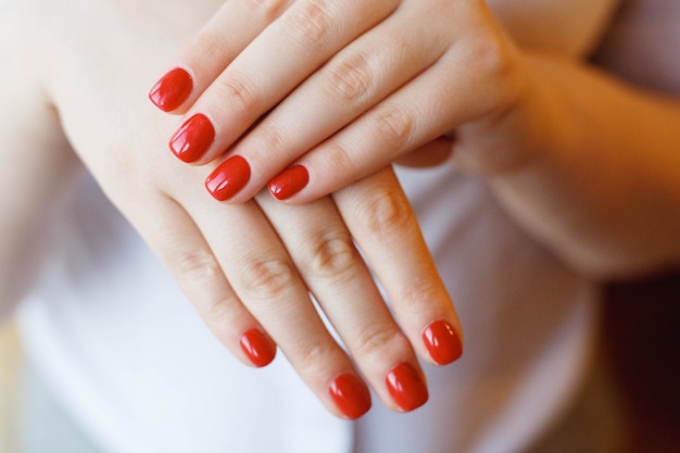 Closeup of hands of a young woman with red manicure on nails.