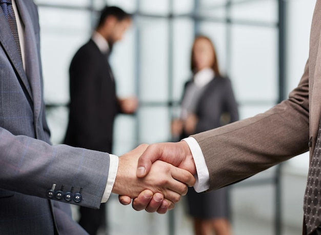 Closeup of a handshake of business partners against the background of colleagues