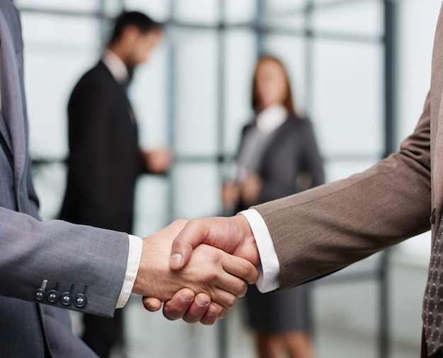 Closeup of a handshake of business partners against the background of colleagues