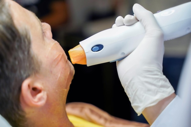 Closeup handsome man having color light therapy to stimulate facial skin wellbeing