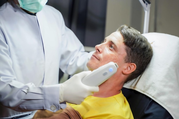 Closeup handsome man having color light therapy to stimulate facial skin