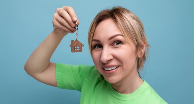 Closeup of a happy joyful cute blond girl in a casual look who shows off buying a home on a blue