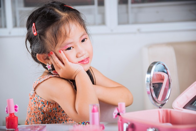 Closeup of happy kid is beautiful make up face with cosmetics toy