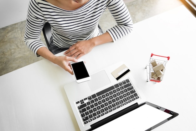 Closeup of happy young woman holding credit card inputting card information while and using smart phone at home. Online shopping concept.