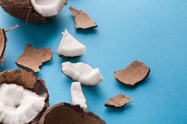 Closeup healthful coconuts on a light blue background. Hawaiian coconut cut in pieces. Organic ingredients for cooking vegan meals. Nutritious exotic nuts.