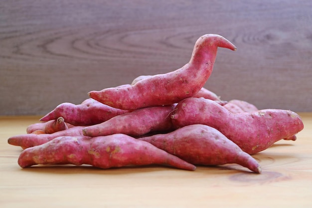 Closeup of Heap of Raw Purple Sweet Potatoes on Wooden Background