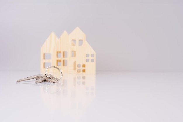 closeup house keys against the background of wooden house models