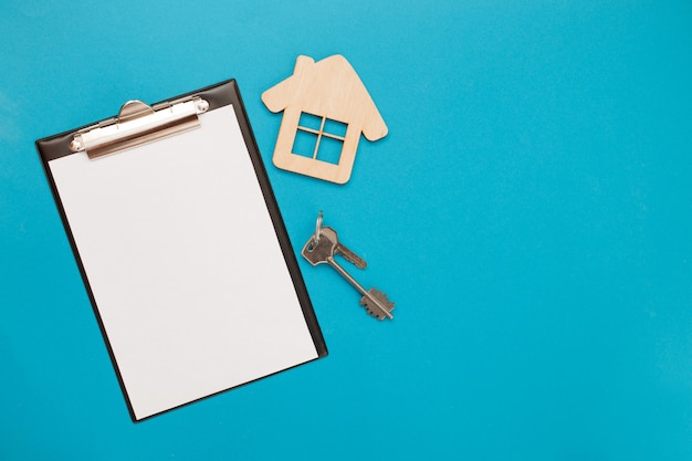 Closeup of house wooden model and keys with blank for text on blue