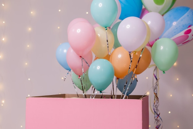 Closeup of a huge pink box with colorful balloons inside birthday present surprise holiday goods