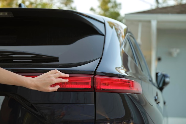 Closeup of human hand on rear car stoplight checkout before driving Safety travel concept