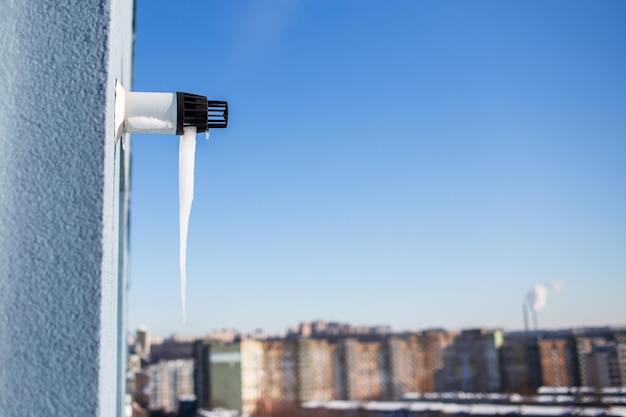 Closeup of icicle on gas boiler chimney in winter time Flue of gas boiler in apartment