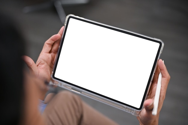 Closeup image of an Asian man using his digital tablet in a room